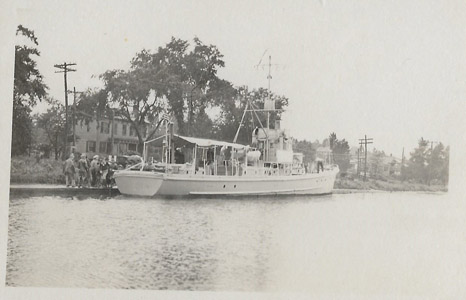United States Submarine Chaser No. 252 is shown possibly at South Bound Brook in the Delaware and Raritan Canal during the First World War.  The SC252 was a SC-1 Class submarine chaser, a large class of anti-submarine vessels designed at the direction of then-Assistant Secretary of the Navy Franklin D. Roosevelt, who ordered the Navy to design a small, wood-constructed, anti-submarine vessel that could be built quickly in civilian boatyards to combat attacks by German U-boats.  Commissioned on March 7, 1918, the SC252 was 110 feet in length and displaced 85 tons.  She was armed with a 76 mm gun, two .30 caliber Colt machine guns and depth charges.  During World War I, the government used the Delaware and Raritan Canal as a safe corridor to transport boilers and naval supplies to the Brooklyn Navy Yard from Philadelphia and Washington, D.C., while the canal itself was guarded by troops at strategic points.